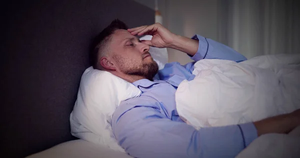 不眠症のベッドで目を覚ます男 眠りの悪夢 — ストック写真