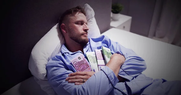 紙幣の束が付いているベッドで寝ている男 — ストック写真