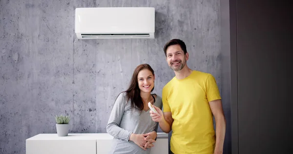 Gelukkig Jong Paar Aanpassen Temperatuur Van Airconditioning Door Afstandsbediening — Stockfoto