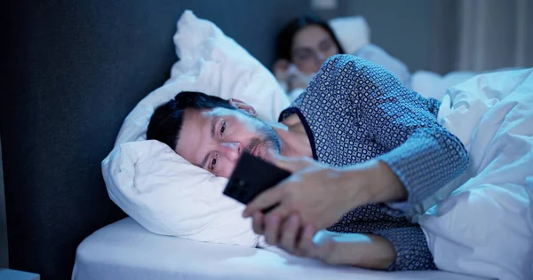 Ung Man Använder Mobiltelefon Tag Hennes Fru Sitter Sängen Natten — Stockfoto