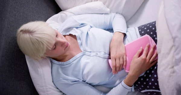 Jonge Vrouw Met Hot Water Bottle Maag Liggend Bed — Stockfoto
