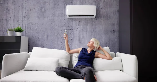 Gelukkig Jonge Vrouw Met Afstandsbediening Ontspannen Onder Air Conditioner — Stockfoto
