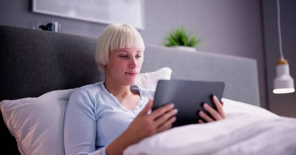 Yatakta Uzanmış Aydınlanmış Dijital Tablet Bakan Kadın — Stok fotoğraf