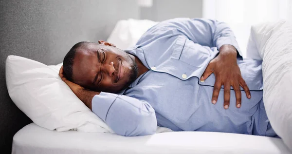 Afrykańczyk Siedzący Łóżku Cierpiący Ból Brzucha — Zdjęcie stockowe