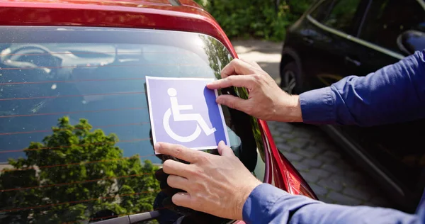 司机将轮椅贴纸贴在汽车上 — 图库照片