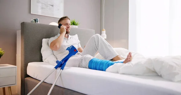 Happy Young Man Broken Leg Sitting Sofa Talking Mobile Phone — Stock Photo, Image
