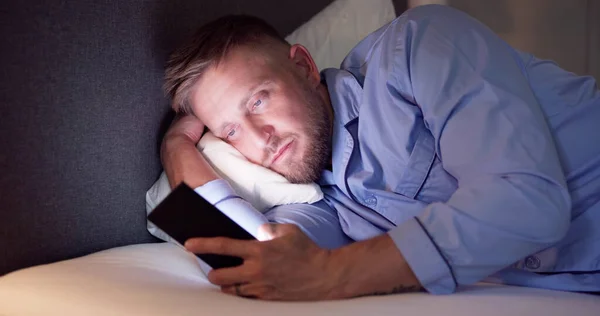 Άνθρωπος Ξαπλωμένος Στο Κρεβάτι Χρησιμοποιώντας Κινητό Τηλέφωνο Νύχτα — Φωτογραφία Αρχείου