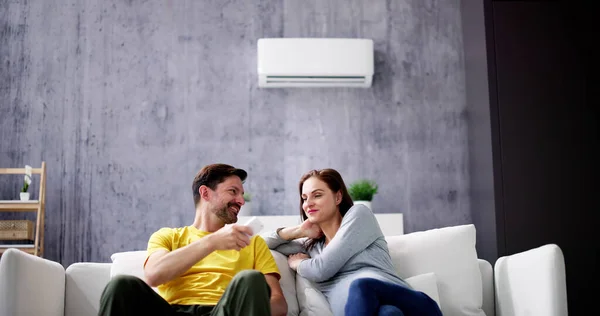 Happy Young Couple Adjusting Temperature Air Conditioner Remote — Stock Photo, Image