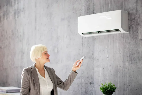 Wanita Muda Yang Bahagia Menggunakan Air Conditioner Dengan Remote — Stok Foto