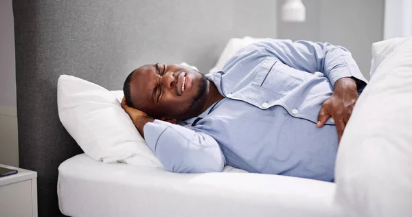 Αφρικανός Που Κάθεται Στο Κρεβάτι Και Υποφέρει Από Στομαχόπονο — Φωτογραφία Αρχείου