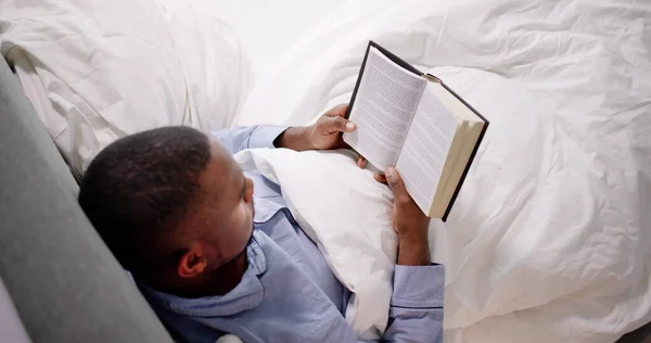 Szczęśliwy Młody Człowiek Afryki Czytając Jego Książkę Łóżku — Zdjęcie stockowe
