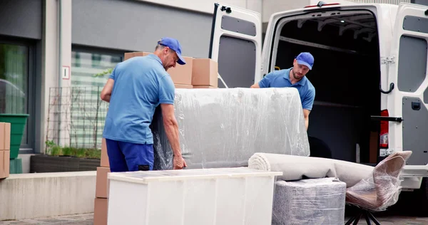 身穿蓝色制服的男工从卡车上卸下家具 — 图库照片