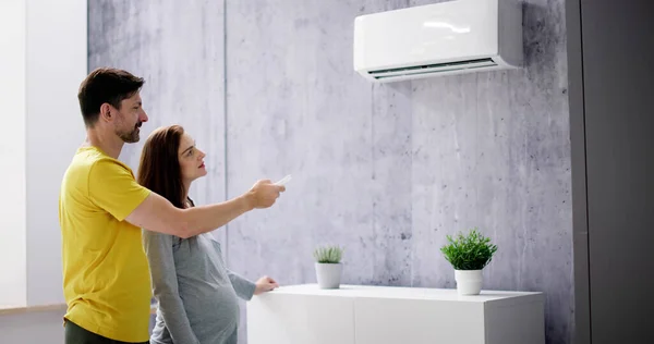Happy Young Couple Adjusting Temperature Air Conditioner Remote — Stock Photo, Image