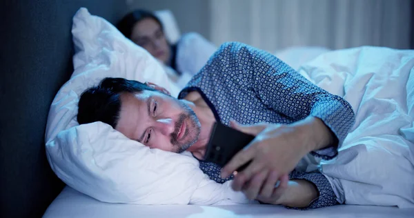 Ung Man Använder Mobiltelefon Tag Hennes Fru Sitter Sängen Natten — Stockfoto