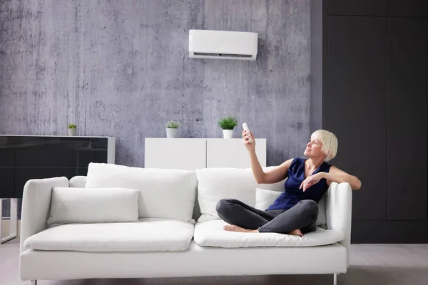 Happy Young Woman Holding Remote Control Relaxing Air Conditioner — Stock Photo, Image