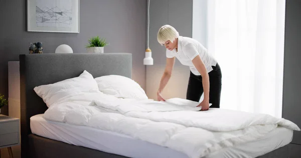 旅馆房间里的年轻女管家换床 — 图库照片