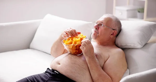 坐得过多的食物生活方式 超重人士看电视 — 图库照片