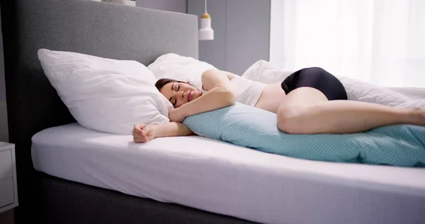 妊娠中の女性は特別な枕でベッドで寝る — ストック写真