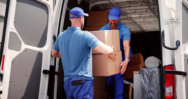 Male Movers In Uniform Loading Delivery Truck