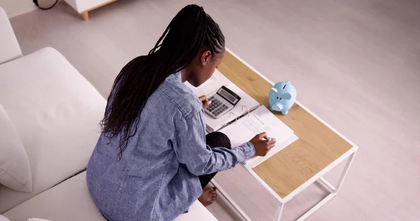 若いアフリカ女性の計算機と請求書を計算します — ストック写真