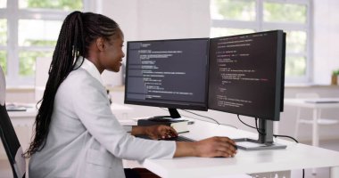 Afrika kökenli Amerikalı programcı masadaki bilgisayarı kullanıyor. Web Geliştirici Kadın