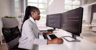 Afrika kökenli Amerikalı programcı masadaki bilgisayarı kullanıyor. Web Geliştirici Kadın