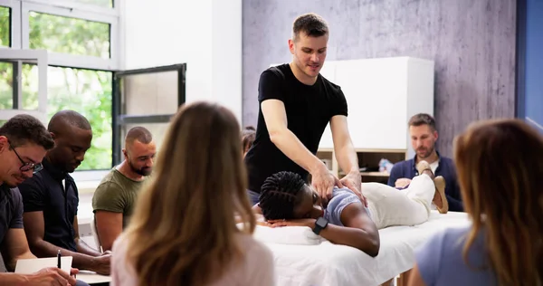 Male Instructor Teaching Massage Technique To Group Of Multi-ethnic People