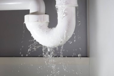 Beyaz lavabo borusundan su sızıyor.