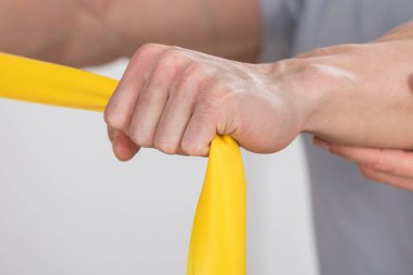 Bir fizyoterapistin insana egzersiz bandıyla eğitim verdiği yakın plan.