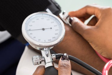 Hastaların kan basıncını steteskopla ölçen doktorun yakın çekimi.