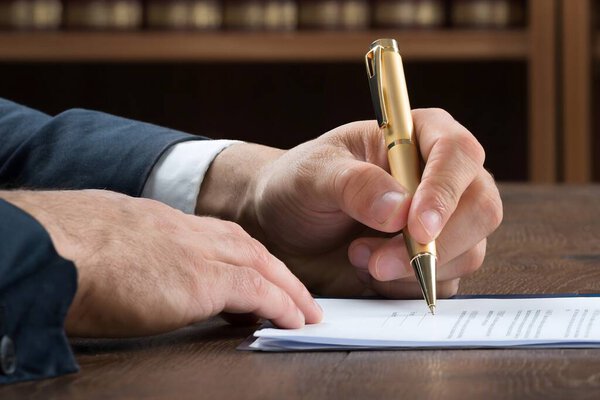 Обрезанное изображение адвоката-мужчины, пишущего на юридических документах в зале суда
