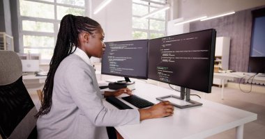 Afrika kökenli Amerikalı programcı masadaki bilgisayarı kullanıyor. Web Geliştirici Kadın
