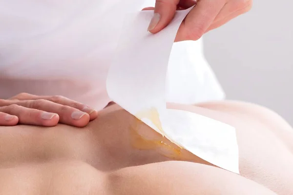 Close-up Of A Woman Waxing Man\'s Chest With Wax Strip