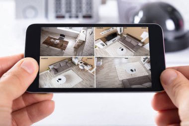 Ekranda CCTV kamera görüntüsü olan bir kişinin el kameralı cep telefonunun yakın çekimi