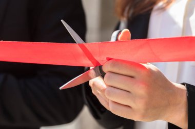 İş adamları el kesme kırmızı kurdele makas ile yakın çekim