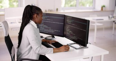 Afrika kökenli Amerikalı programcı masadaki bilgisayarı kullanıyor. Web Geliştirici Kadın