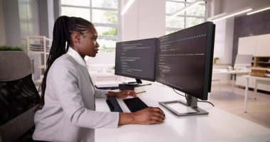 Afrika kökenli Amerikalı programcı masadaki bilgisayarı kullanıyor. Web Geliştirici Kadın
