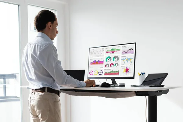 Man Working On Computer At Standing Desk In Home Office
