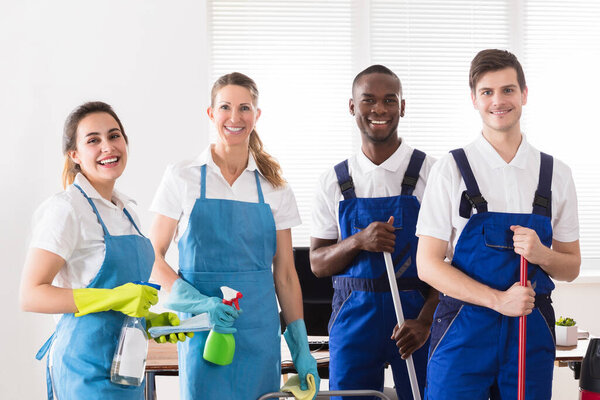 Portrait Of Happy Diverse Janitors In The Office With Cleaning Equipments
