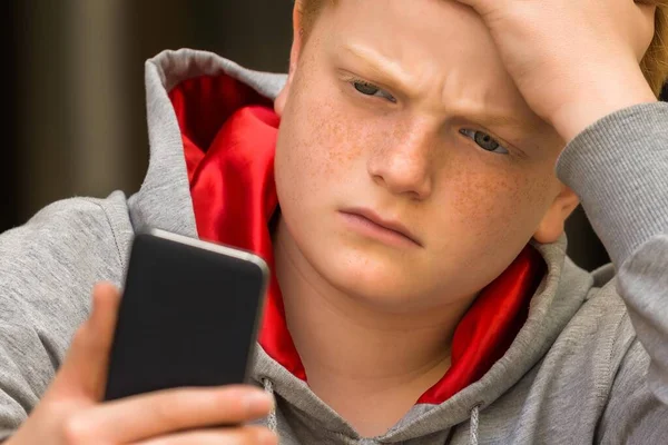 Smutny Chłopiec Ogląda Telefon Komórkowy Ręki Głowie — Zdjęcie stockowe