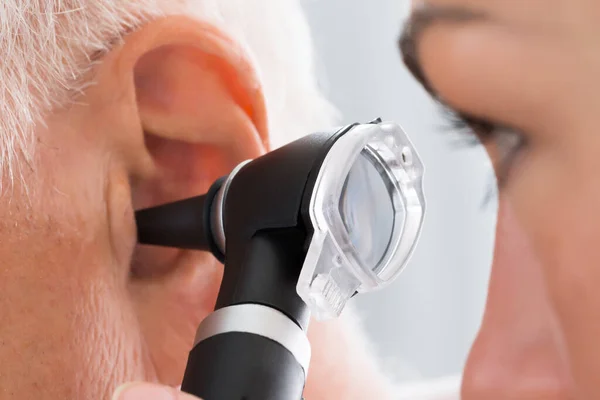 聴診器で患者さんの耳を調べる女医さんのクローズアップ — ストック写真