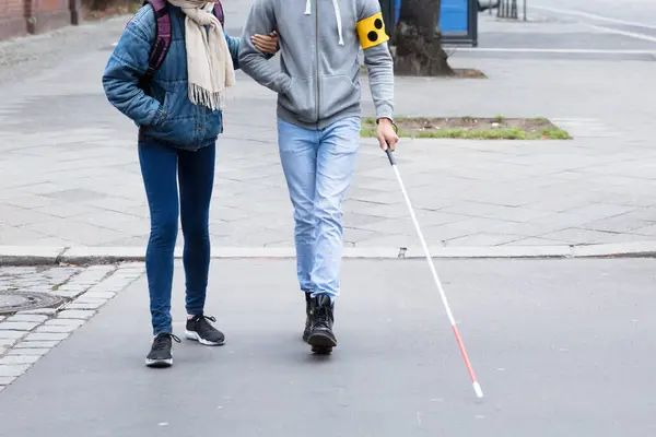 年轻妇女帮助盲人用白棍子 当横穿路 — 图库照片