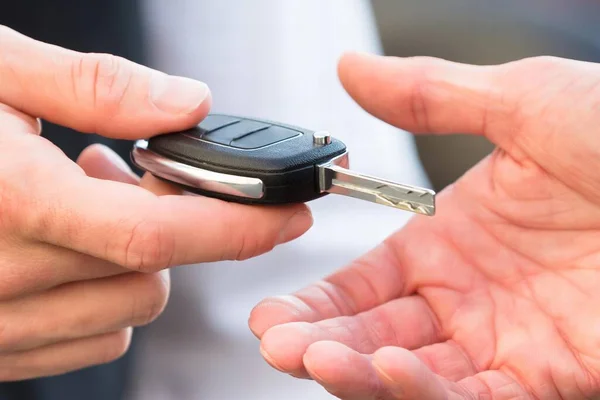 Close-up Of Valet\'s Hand Giving Car Key To Businessperson