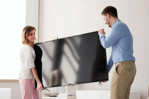 Happy Young Couple Excitedly Carrying Their New TV