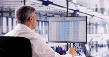 Hospital Doctor Using Spreadsheet For Billing Codes On Desktop