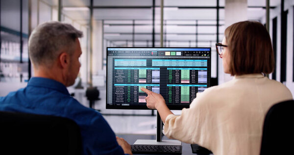 Аналитик, работающий над таблицей с помощью настольного компьютера