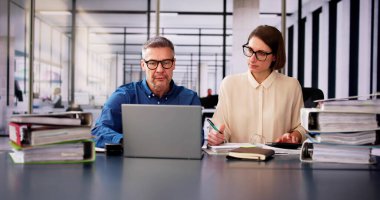 Ofiste Dizüstü bilgisayar kullanırken Faturayı Hesaplayan İki İşadamı