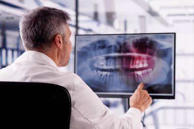 Doktor ve dişçi bilgisayar masaüstündeki röntgene bakıyor