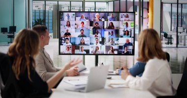 Bir grup iş adamı başka bir iş ekibiyle video konferansı yapıyor.