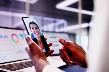 Akıllı telefondaki Webinar 'a katılırken dizüstü bilgisayarında KPI gösterge tablosu ile uzaktan konferans yöneten Afrikalı Amerikalı kadın..